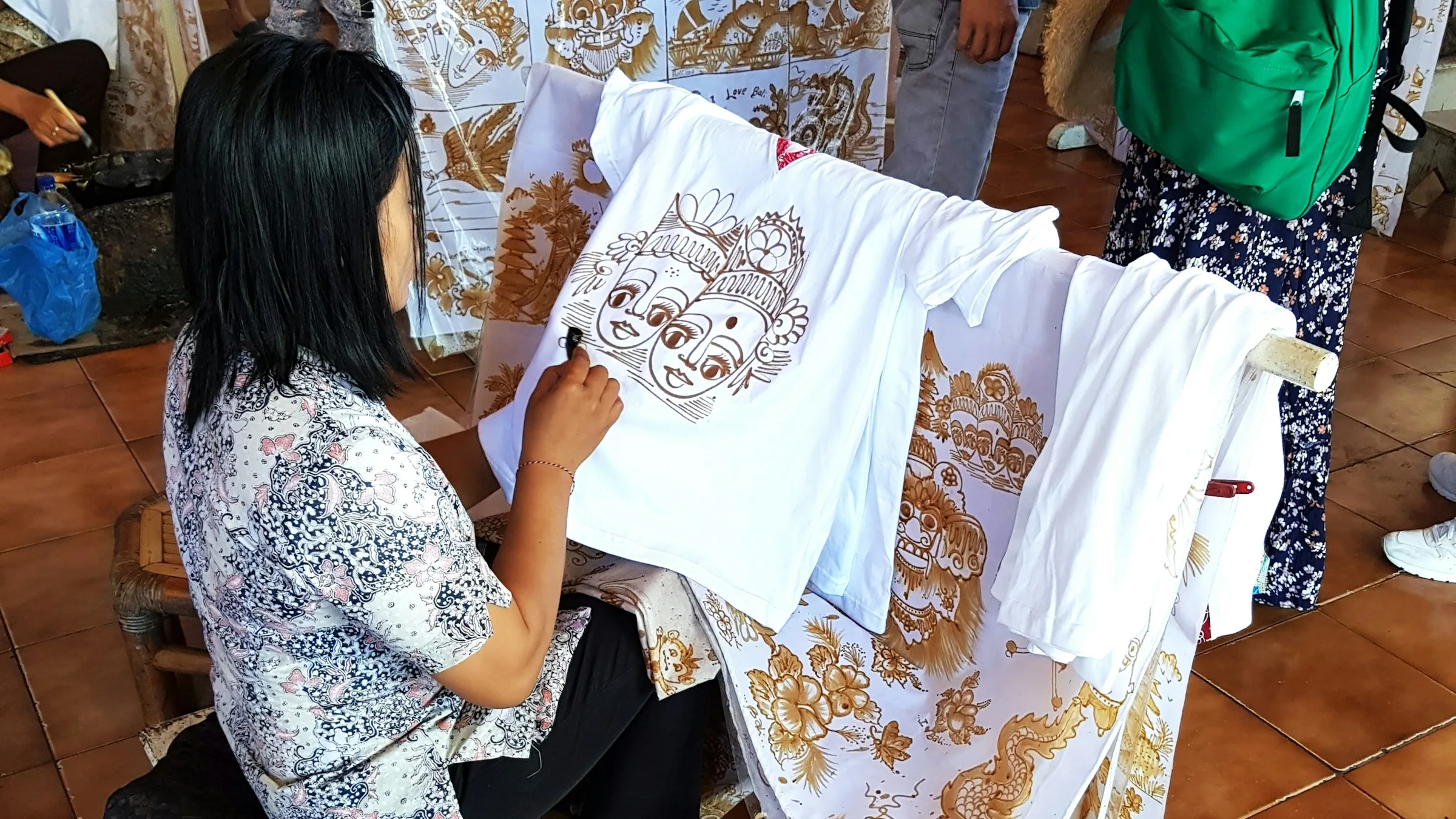 Seorang pembatik menggambar motif dengan canting di atas kain mori, Pekalongan