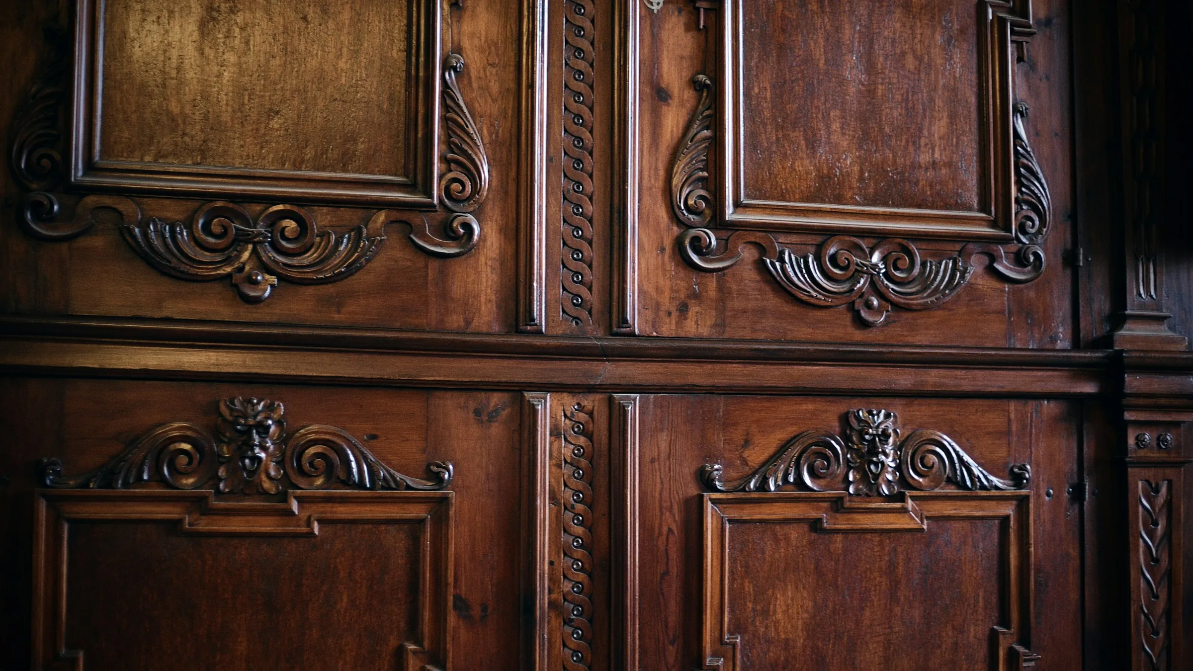 Panel kayu gelap dengan ukiran ornamen tradisional yang rumit